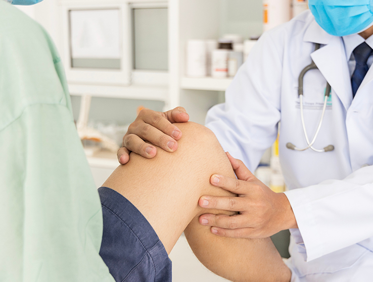Orthopaedic surgeon in white gown examining patient in clinic