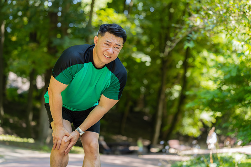 A man suffering from a knee injury while running