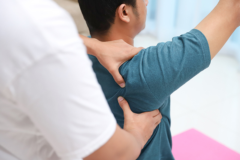 Medical professional assisting a patient with shoulder rehabilitation exercise.